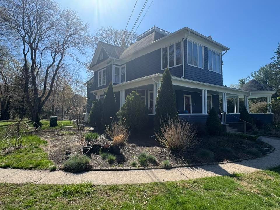 Garden beds around a blue house before mulching